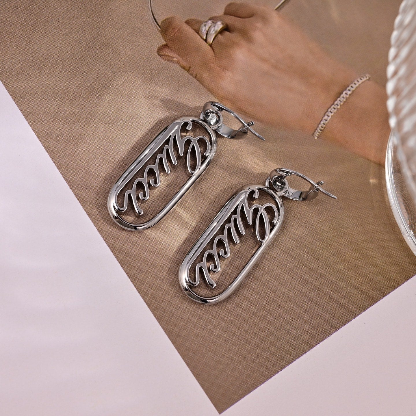 GUCCI 26S SCRIPT LOGO OVAL DROP EARRINGS IN SILVER TONE METAL 633780